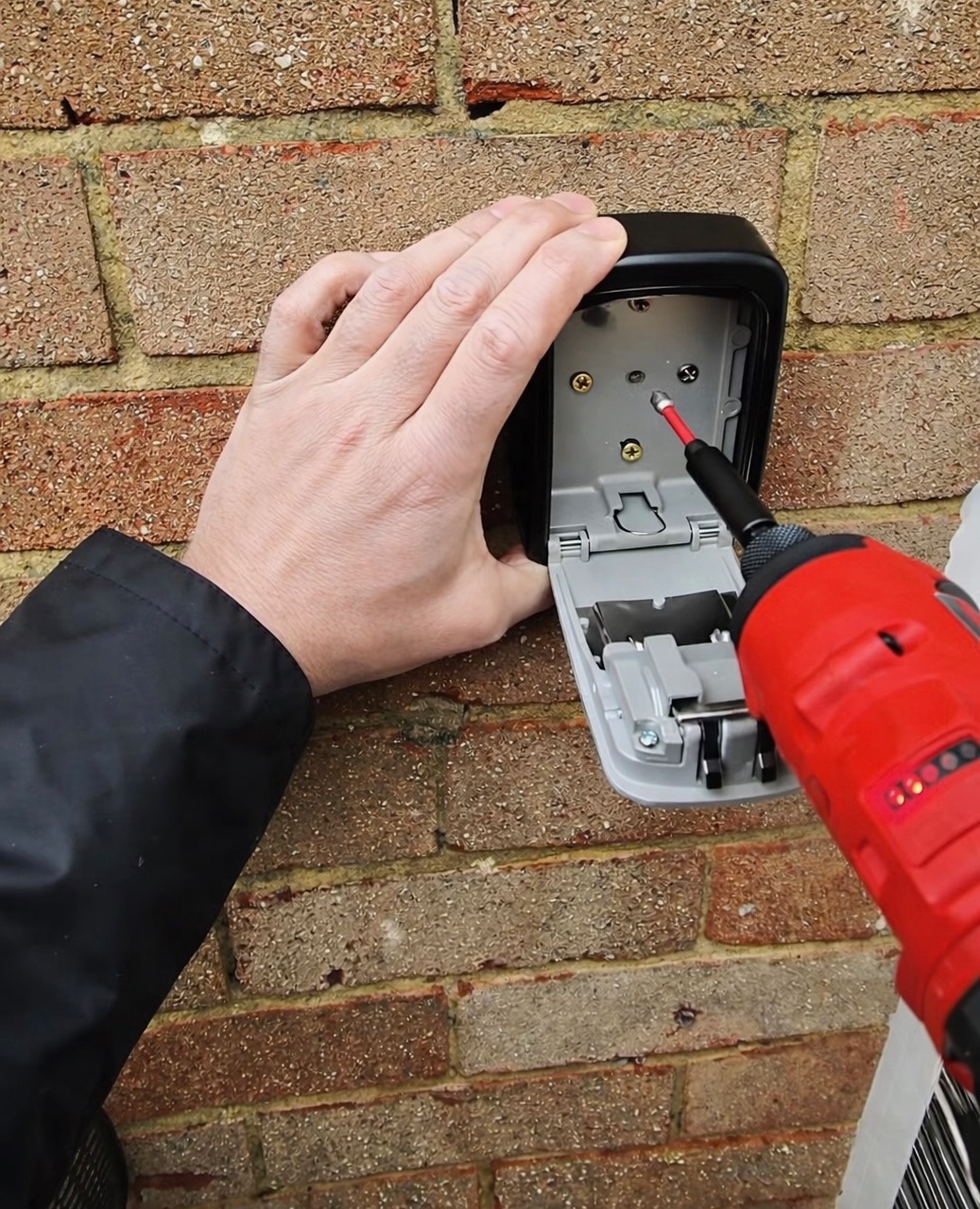 Key safe interior being fixed into brickwork with heavy-duty anchor screws