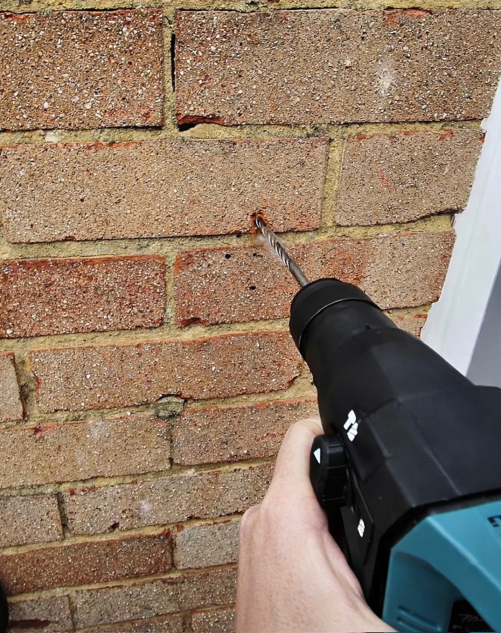Hammer drill creating fixing holes for key safe installation in solid brick